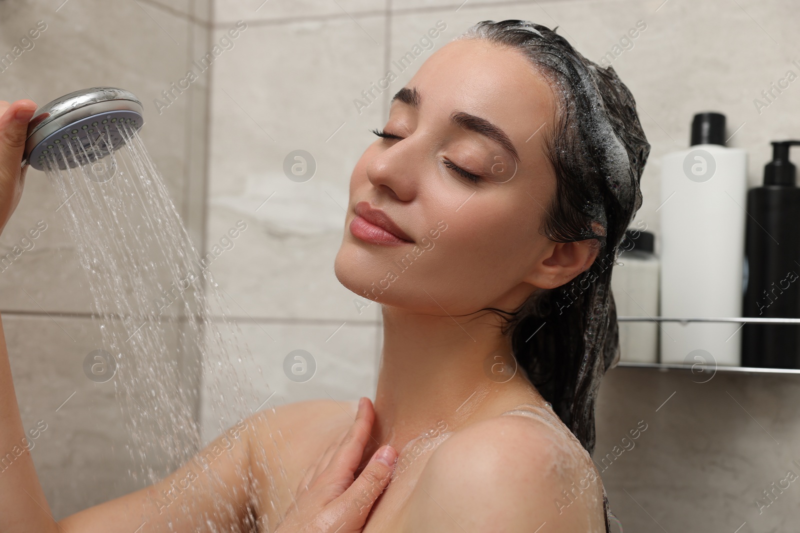 Photo of Beautiful woman taking shower and washing hair indoors