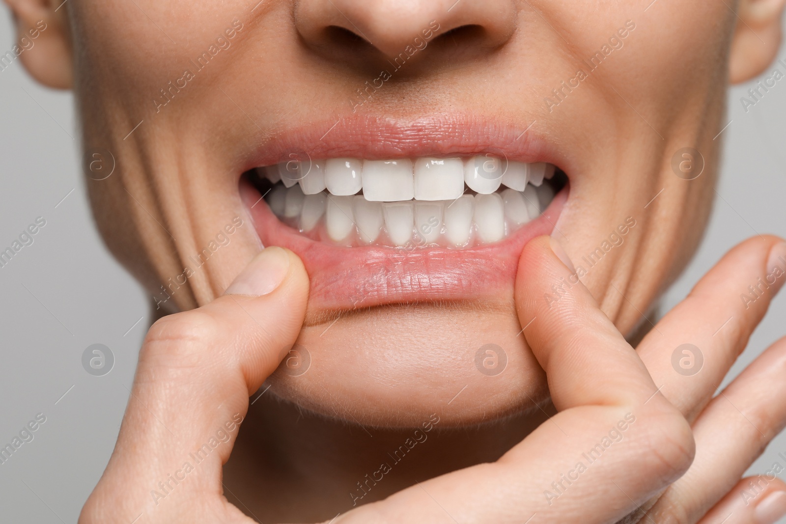 Photo of Woman showing healthy gums on light background, closeup