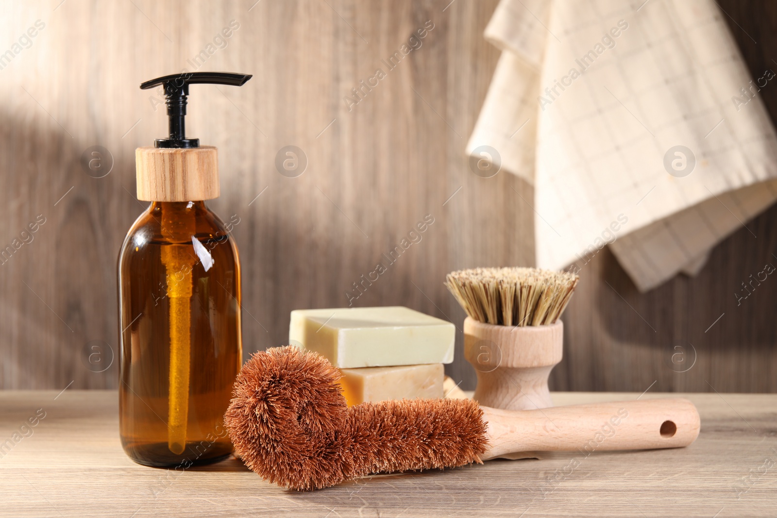 Photo of Cleaning brushes, dispenser and soap bars on wooden table