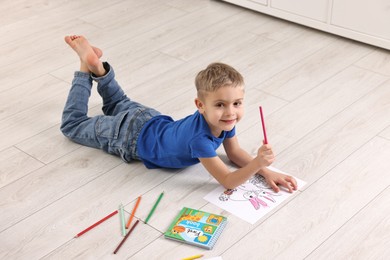 Photo of Cute little boy coloring on warm floor at home. Heating system