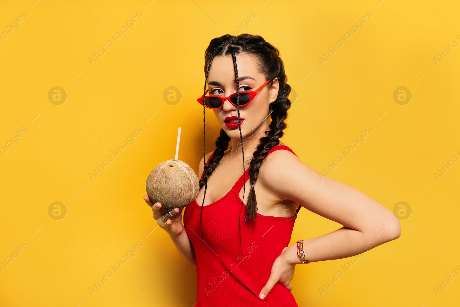 Photo of Young woman with fresh coconut on yellow background. Exotic fruit