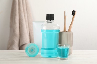 Photo of Mouthwash and other oral hygiene products on white wooden table in bathroom