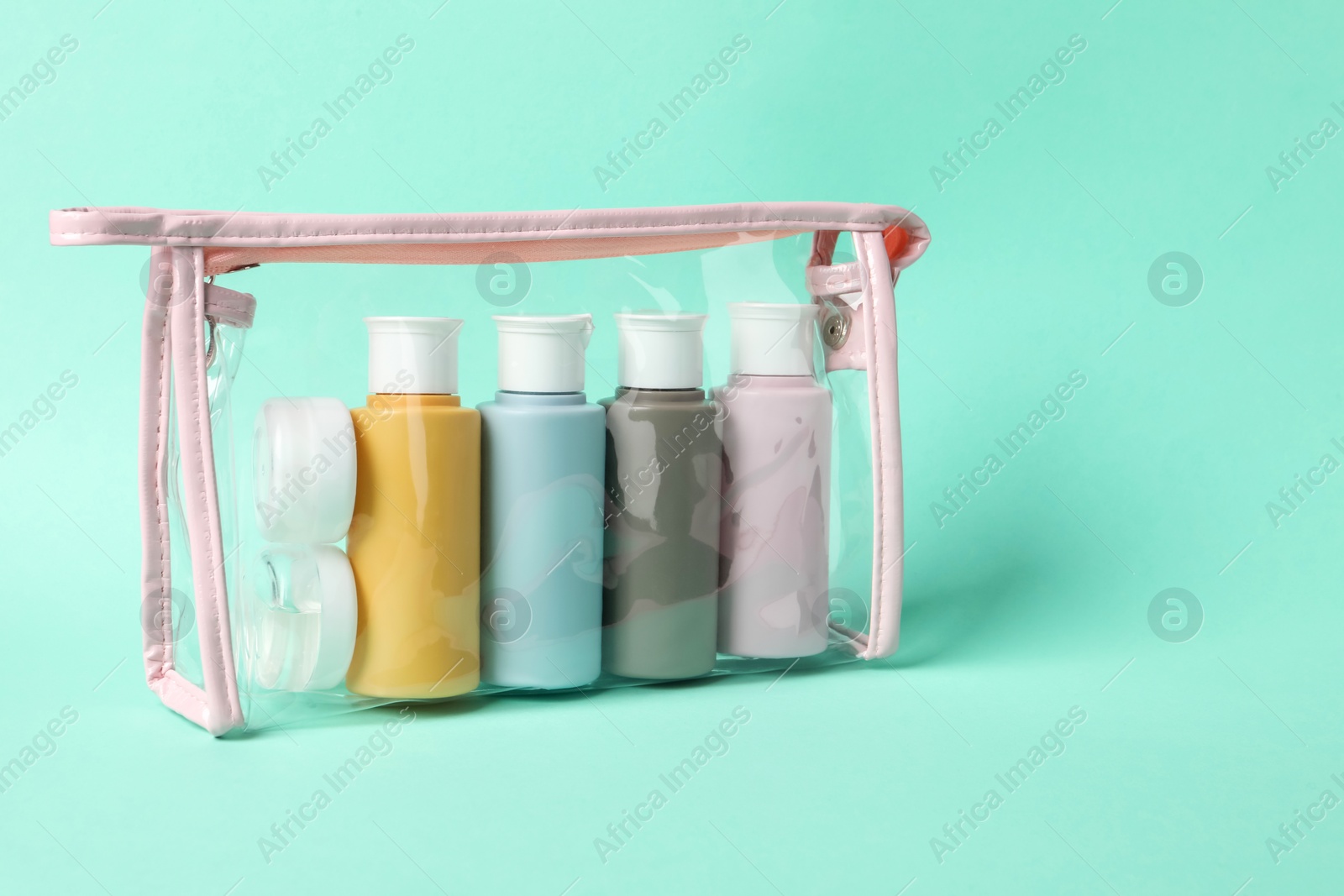 Photo of Cosmetic travel kit in plastic bag on turquoise background. Space for text