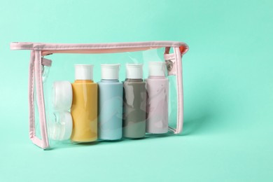 Photo of Cosmetic travel kit in plastic bag on turquoise background. Space for text