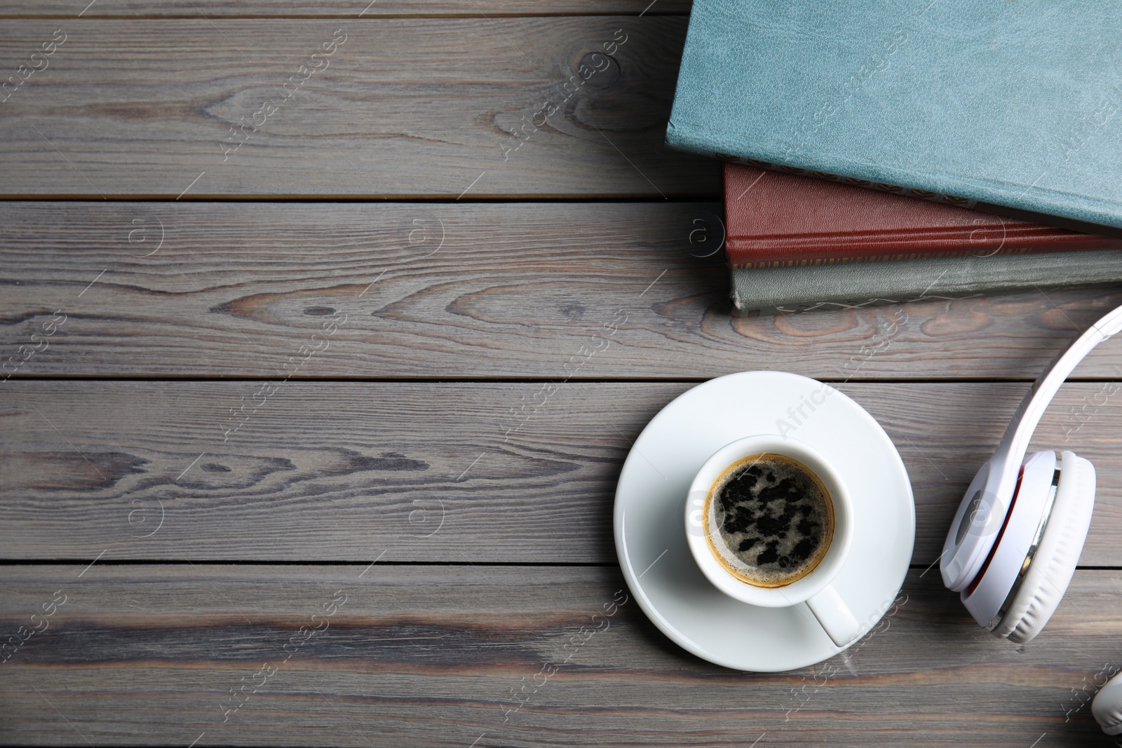 Photo of Books, coffee and headphones on light grey wooden table, flat lay. Space for text