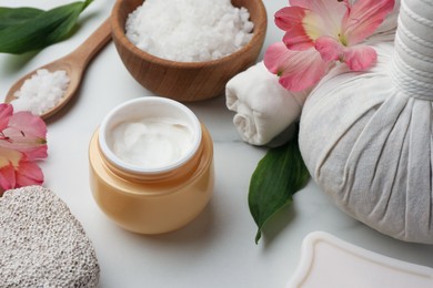 Beautiful composition with spa products and flowers on white marble table, closeup