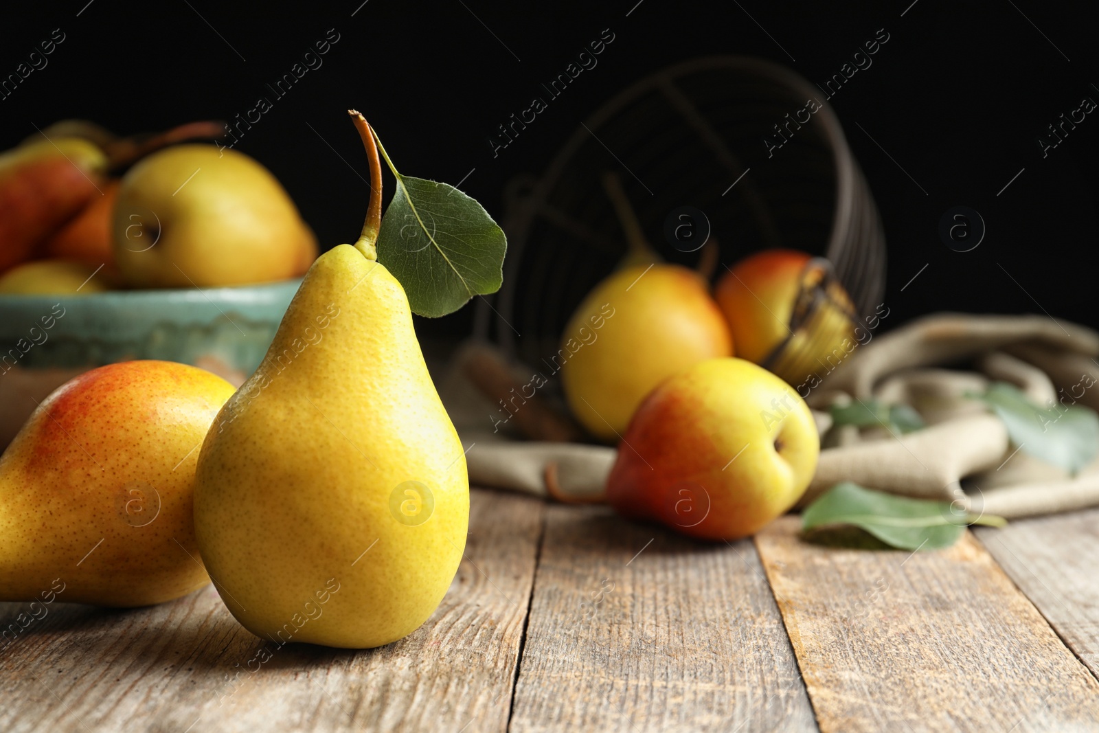 Photo of Ripe pears on wooden table against dark background. Space for text