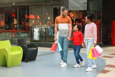 Family shopping. Happy parents and son with colorful bags in mall