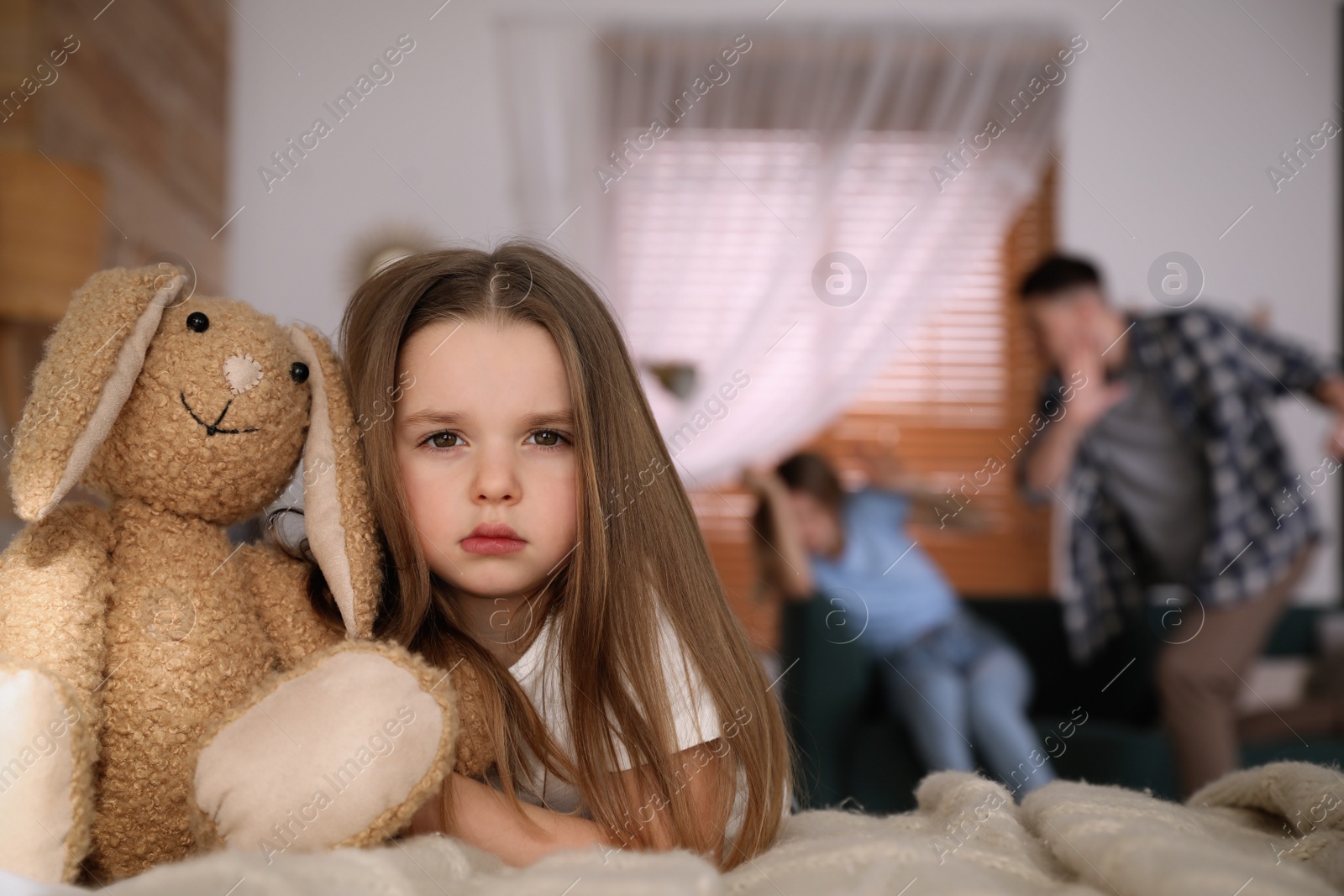 Photo of Couple fighting at home, focus on their unhappy little daughter. Domestic violence