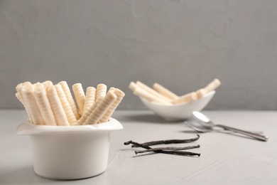 Photo of Bowl with delicious vanilla wafer rolls on table, space for text. Sweet food