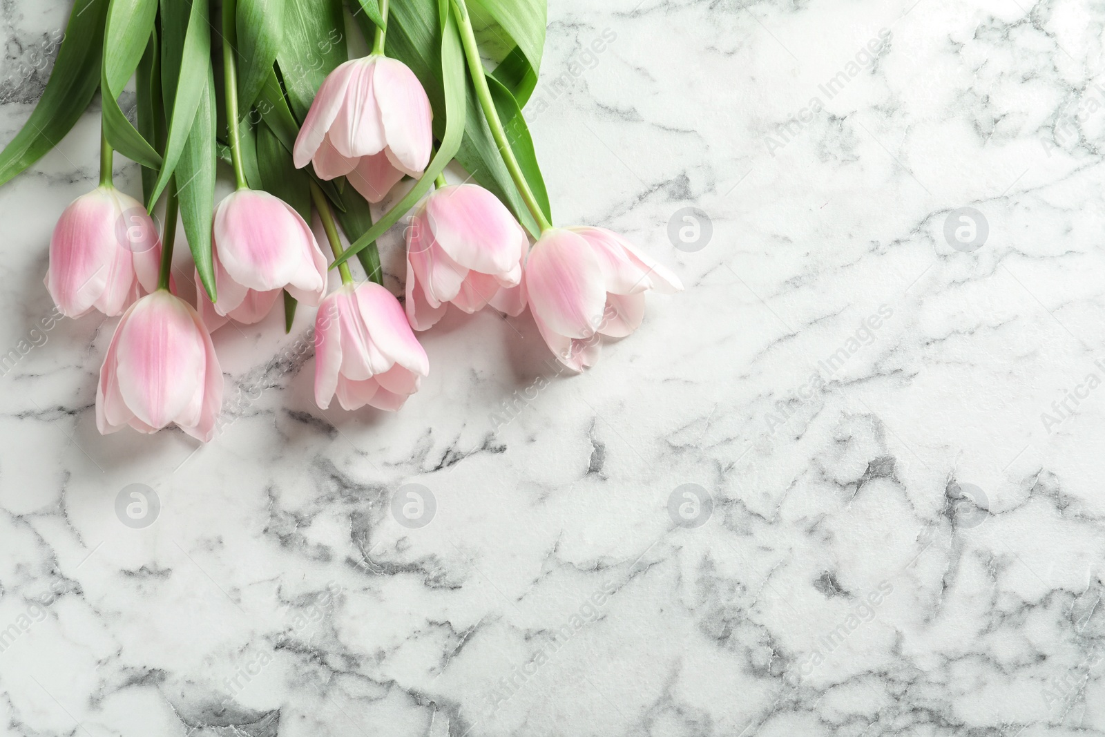 Photo of Beautiful tulips for Mother's Day on marble background, top view