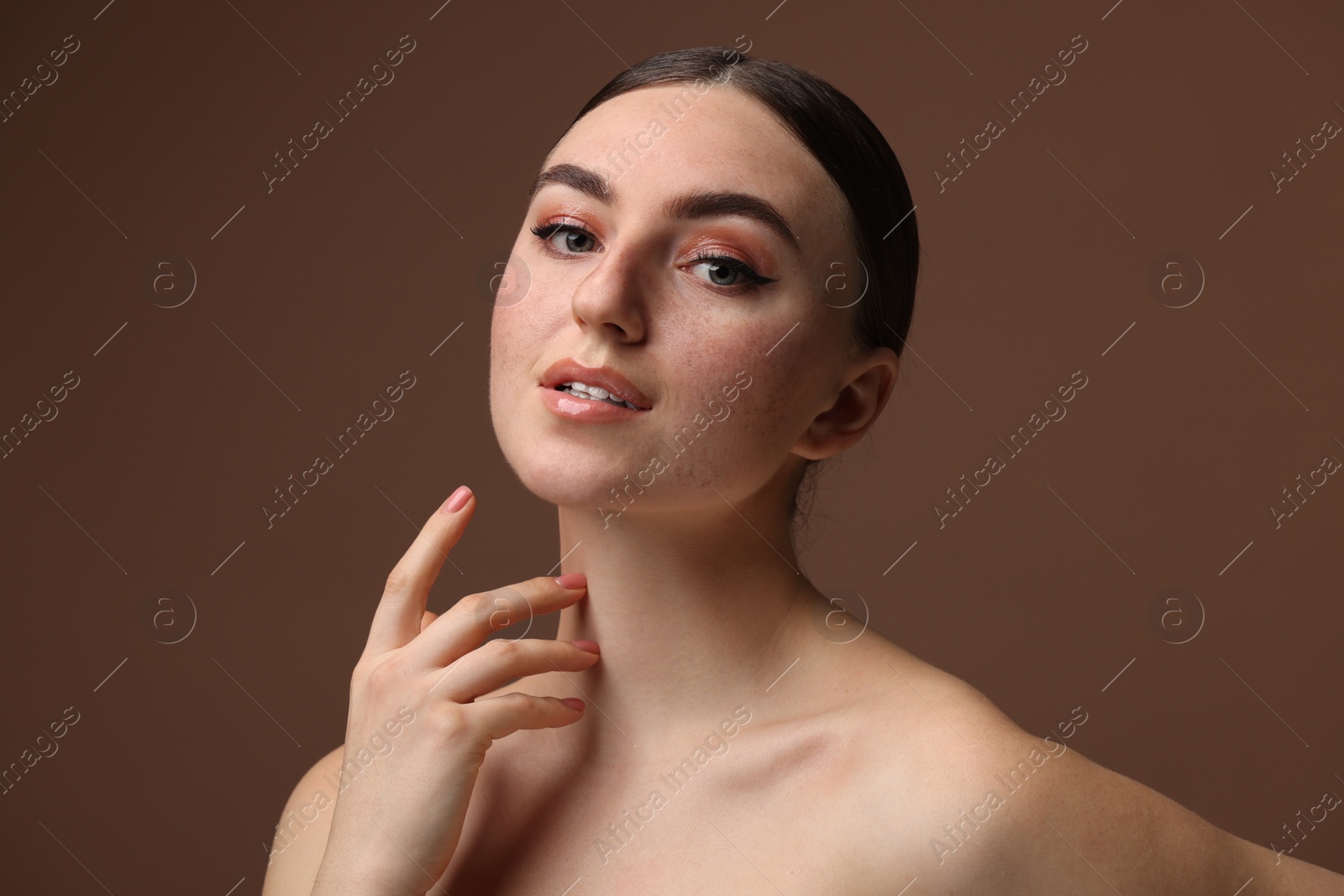 Photo of Portrait of beautiful woman with fake freckles on brown background