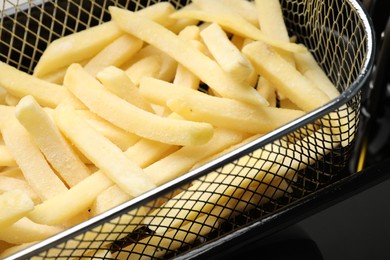 Photo of Uncooked french fries in metal basket, closeup