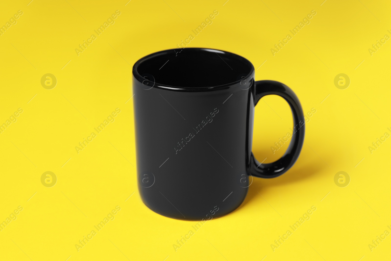 One black ceramic mug on yellow background Photo of One black ceramic mug on yellow background