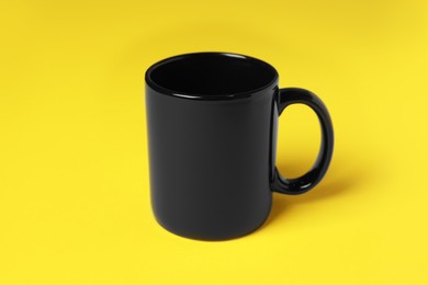 Photo of One black ceramic mug on yellow background
