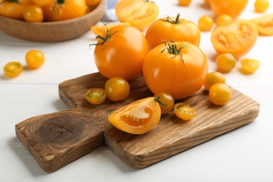 Photo of Ripe yellow tomatoes on white wooden table