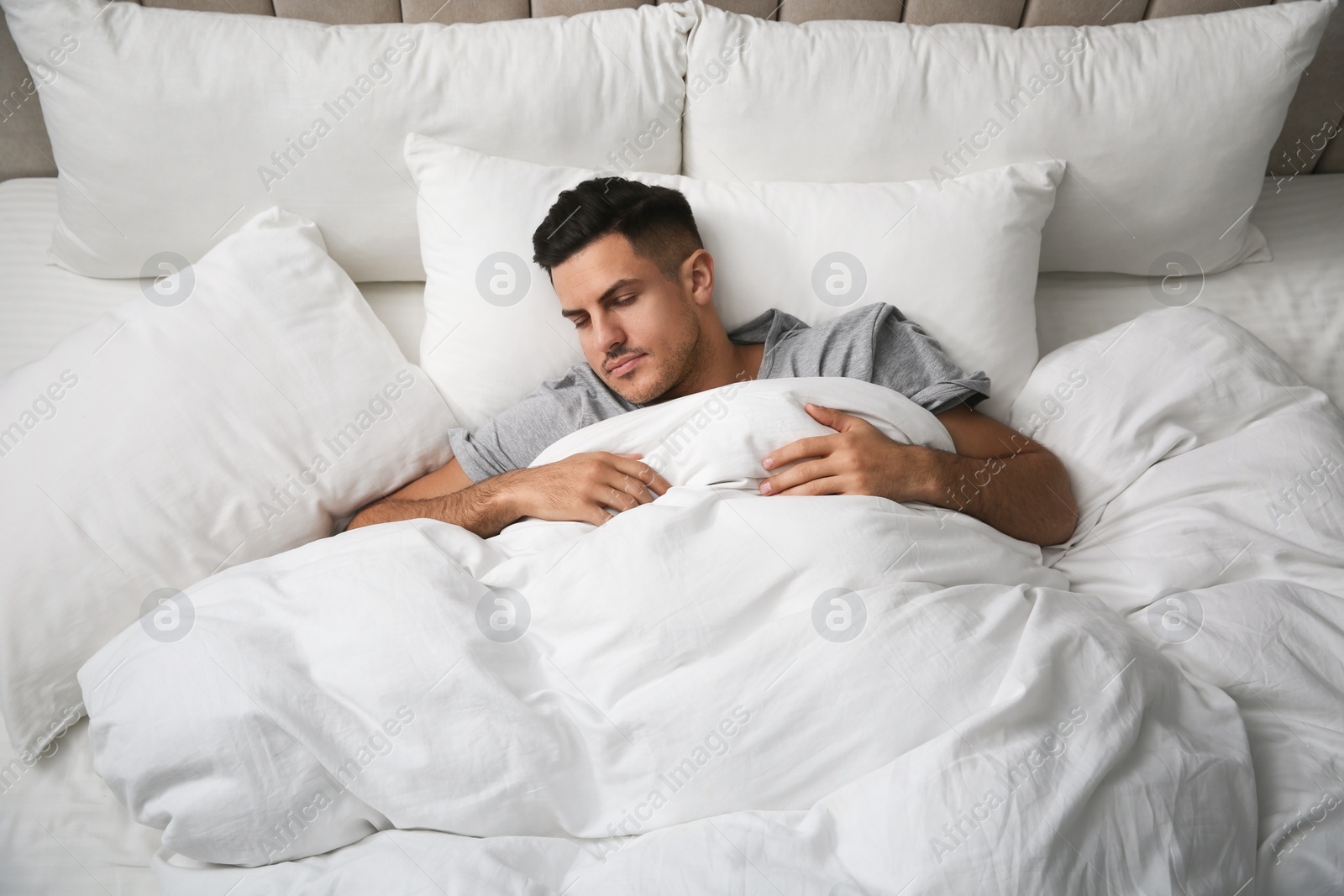 Photo of Handsome man sleeping under soft blanket in bed at home, above view