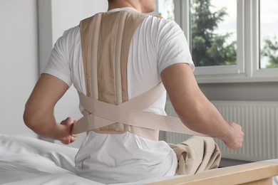 Closeup of man with orthopedic corset sitting in room, back view