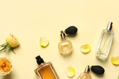 Flat lay composition with different perfume bottles on light yellow background, space for text