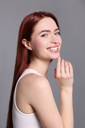 Happy woman with red dyed hair on light gray background