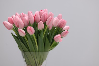 Photo of Bouquet of beautiful pink tulips on grey background, closeup. Space for text