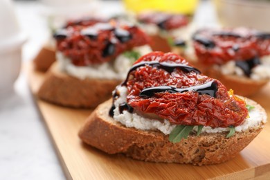 Delicious bruschetta with sun-dried tomato, cream cheese and balsamic vinegar on light table, closeup