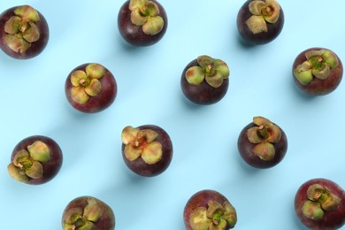 Photo of Fresh ripe mangosteen fruits on light blue background, flat lay