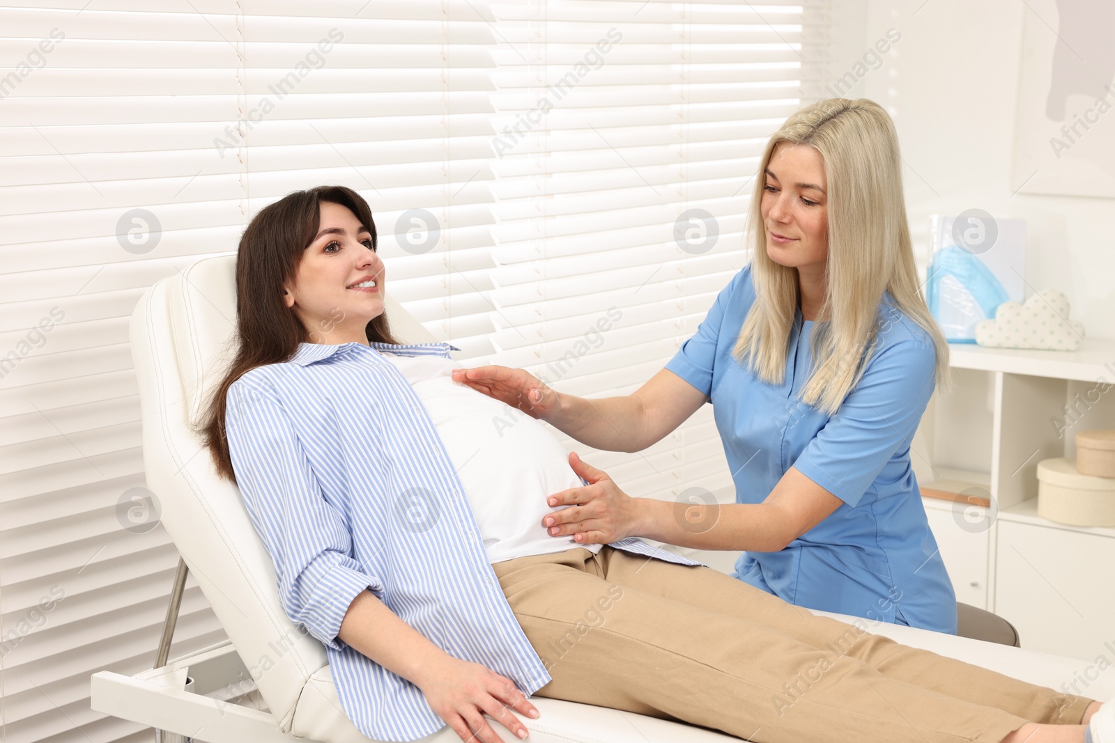 Photo of Pregnancy checkup. Doctor examining patient's tummy in clinic