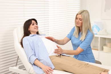 Pregnancy checkup. Doctor examining patient's tummy in clinic