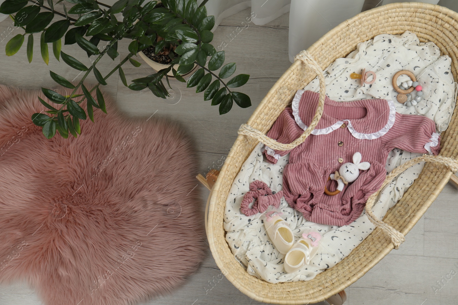 Photo of Cute baby clothes and accessories in basket bassinet at home, top view