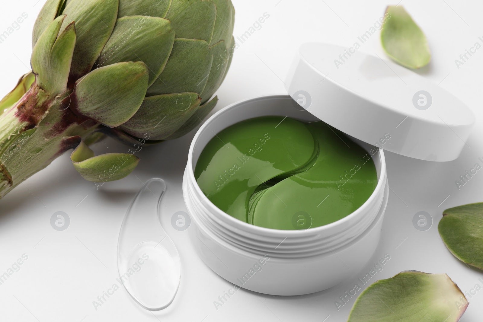 Photo of Package of under eye patches and artichoke on white background. Cosmetic product