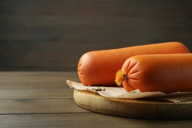 Board with tasty boiled sausages on wooden table, closeup. Space for text