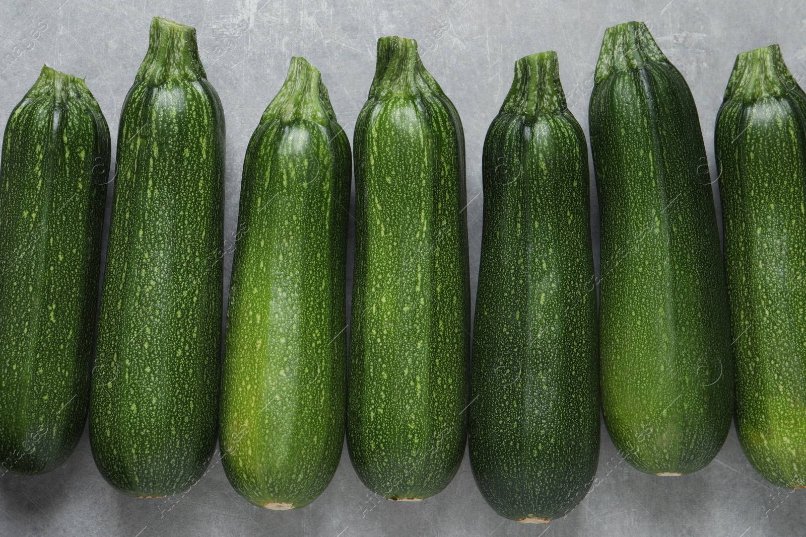 Photo of Raw ripe zucchinis on light grey table, flat lay