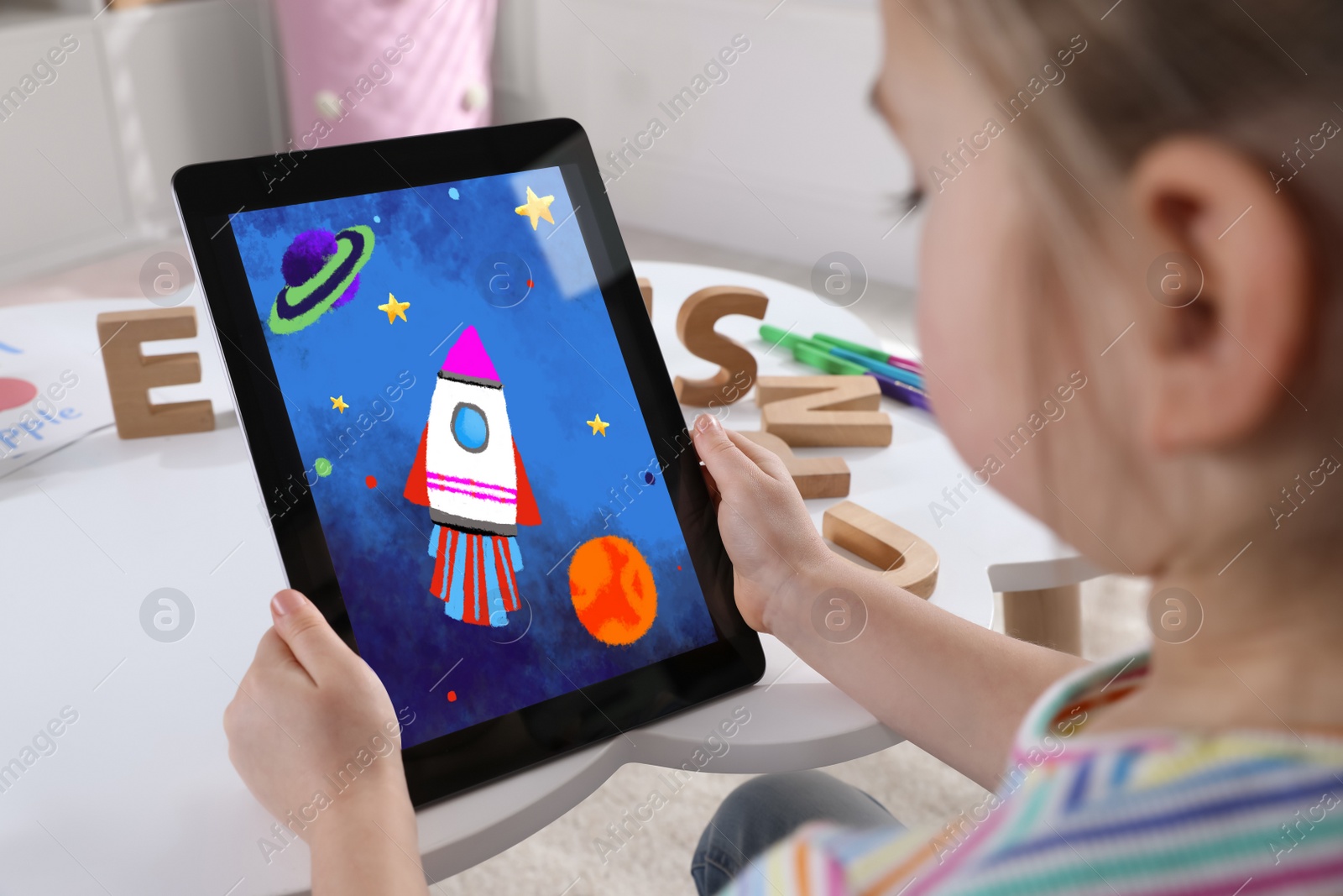 Image of Little girl holding tablet with cute drawing at home. Child art