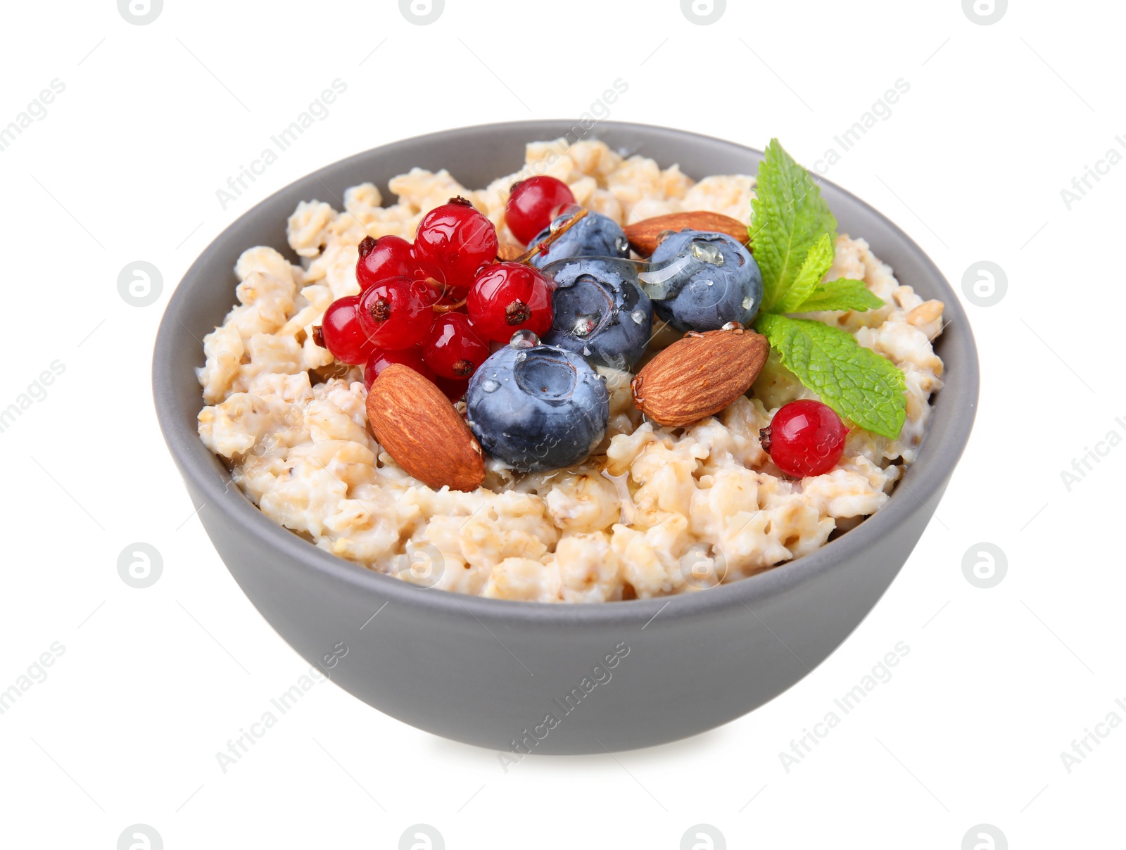 Photo of Ceramic bowl with oatmeal, berries. almonds and mint isolated on white