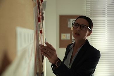 Photo of Detective looking at evidence board in office