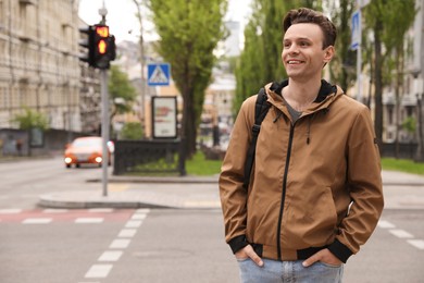 Photo of Young man near pedestrian crossing with traffic lights