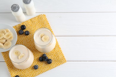 Tasty yogurt, banana and blueberries on white wooden table, top view. Space for text