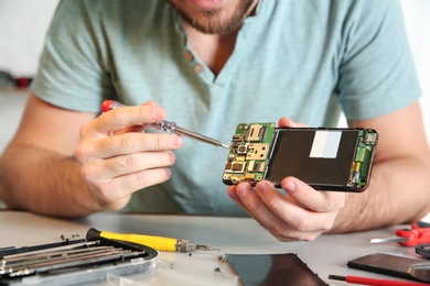 Technician repairing mobile phone at table, closeup