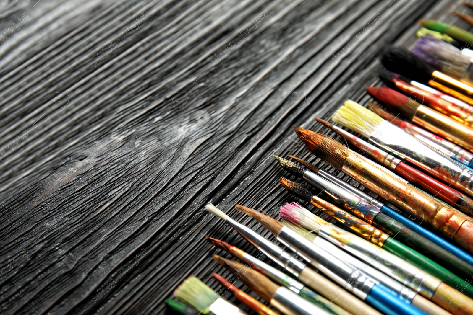 Photo of Different paint brushes on wooden table, closeup. Space for text