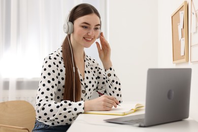 E-learning. Young woman using laptop during online lesson at table indoors