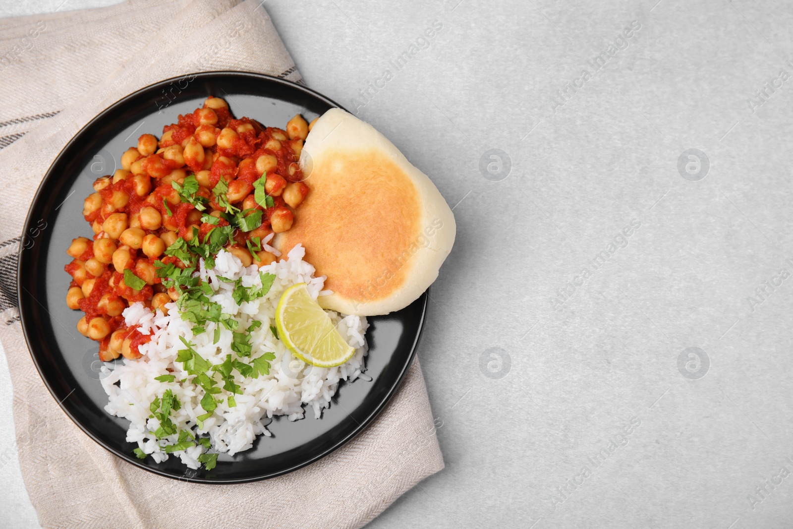 Photo of Delicious chickpea curry with rice and flatbread on light gray table, flat lay. Space for text