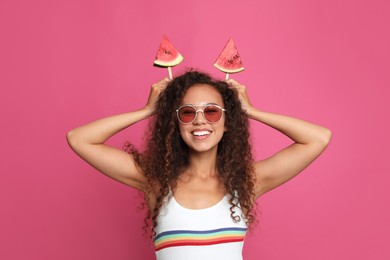 Beautiful young African American woman with pieces of watermelon on crimson background