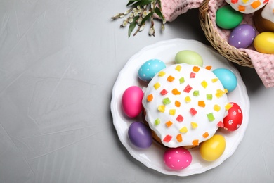 Easter cake and painted eggs on light grey table, flat lay