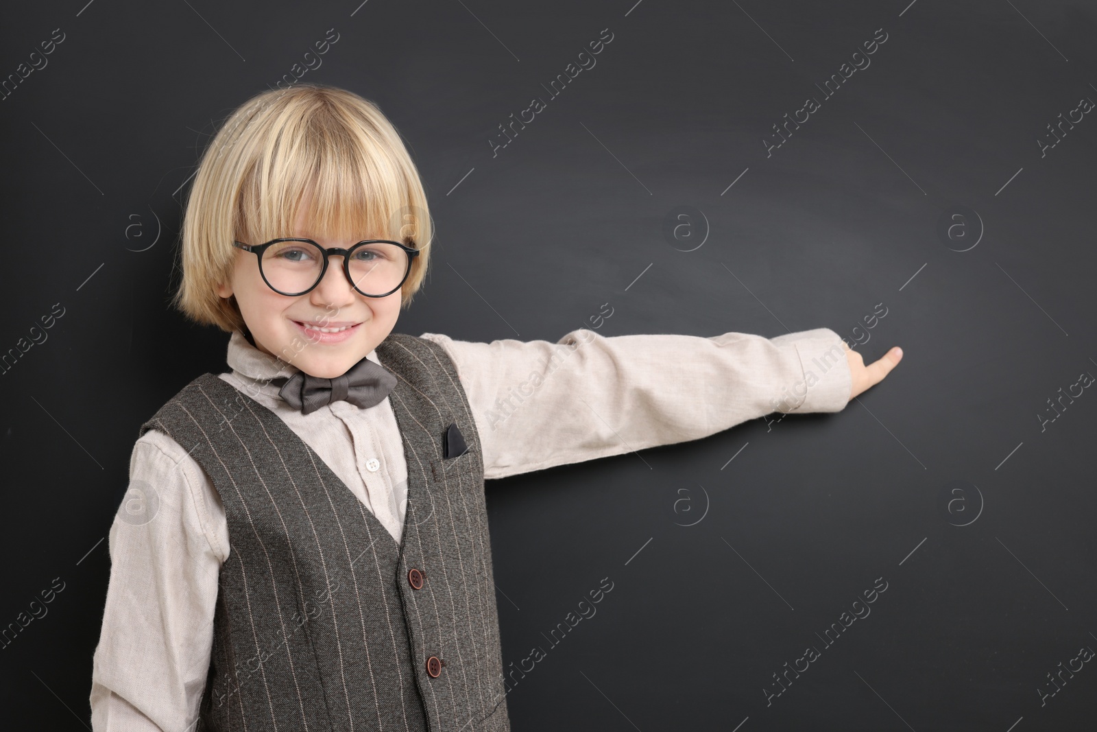 Photo of Happy little school child pointing at chalkboard