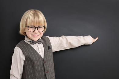 Photo of Happy little school child pointing at chalkboard