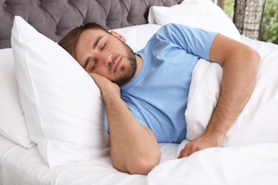 Young handsome man sleeping in bed at home. Early morning