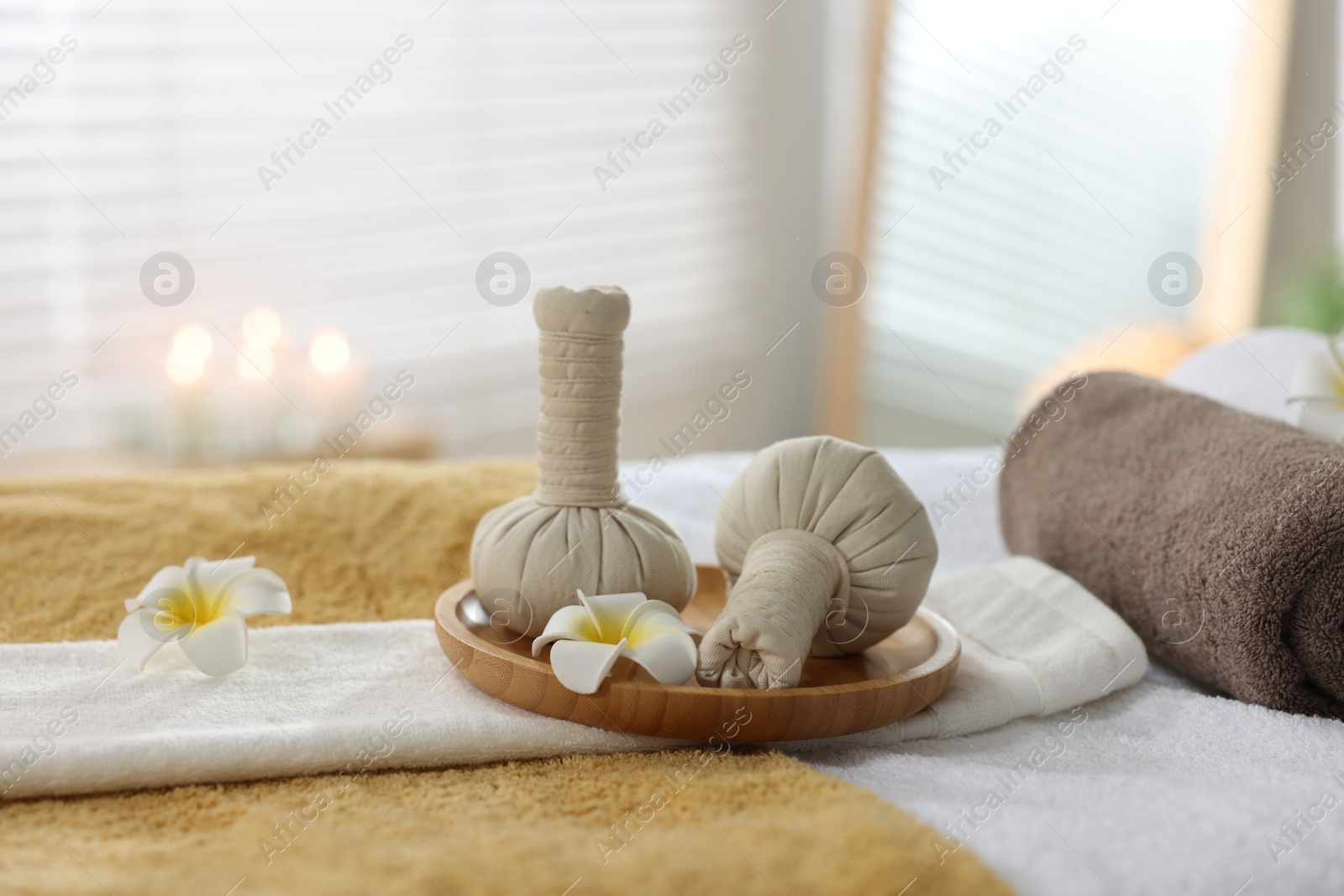 Photo of Herbal bags, flowers and towels on massage table in spa