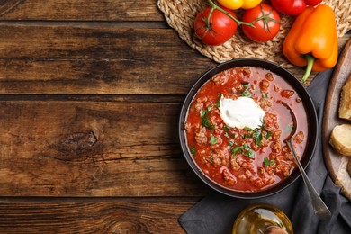 Photo of Bowl of delicious stuffed pepper soup served on wooden table, flat lay. Space for text