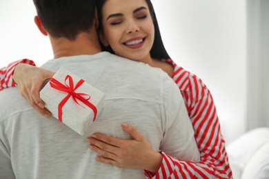 Photo of Lovely couple with gift box at home, closeup. Valentine's day celebration